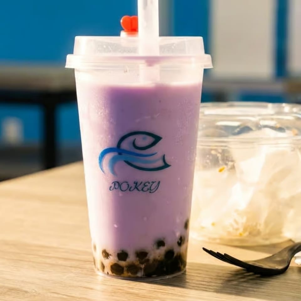 Pokey's taro bubble tea with tapioca pearls and a red heart stopper on a wooden table.