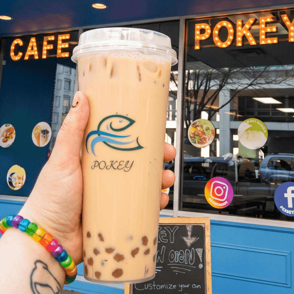 Hand holding a large bubble tea with tapioca pearls in front of Cafe Pokey.
